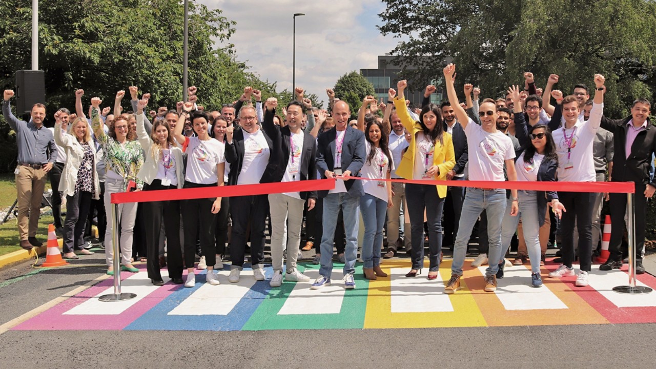 Zróżnicowana grupa uśmiechniętych pracowników Toyoty w koszulkach sieci LGBTIQ+